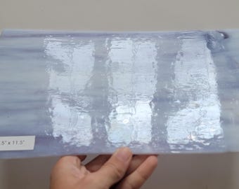 May include: A sheet of iridescent white glass with a subtle blue tint and a wavy pattern. The glass sheet measures 6.5" x 11.5" and has the text "PRD 09 6.5" x 11.5" printed on it.