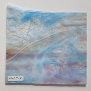 May include: A sheet of iridescent glass with blue, white, and pink swirls. The glass is 8 inches by 7 inches and is labeled "MX 42 8" x 7".