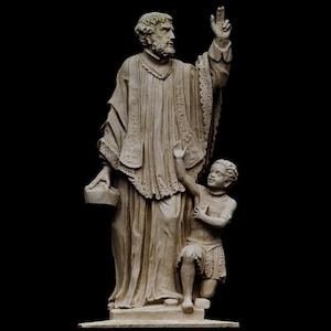 Puede incluir: Una escultura detallada de una figura vestida con una túnica con barba, levantando una mano, y un niño arrodillado. Las figuras son de color beige claro, con detalles intrincados en la ropa y los rasgos faciales. El fondo es negro.