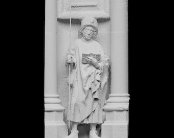 Könnte beinhalten: Graustufen-Skulptur einer bekleideten Figur, die einen Stab und ein Buch hält. Die Figur steht in einem vertieften architektonischen Rahmen, flankiert von Säulen. Die Statue hat ein verwittertes Aussehen.