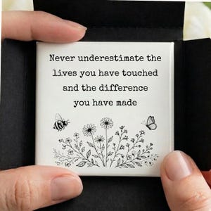 May include: A white square with the text "Never underestimate the lives you have touched and the difference you have made." A bee and butterfly are on the left and right sides of a floral design.