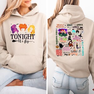 Può includere: Felpa con cappuccio beige con una stampa frontale raffigurante le acconciature di tre streghe e la scritta "TONIGHT We fly". Il retro della felpa presenta varie grafiche e testi a tema Hocus Pocus, inclusi i nomi dei personaggi.