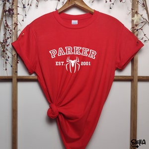 May include: Red t-shirt with white text that reads "Parker Est. 2001" and a white spider graphic.