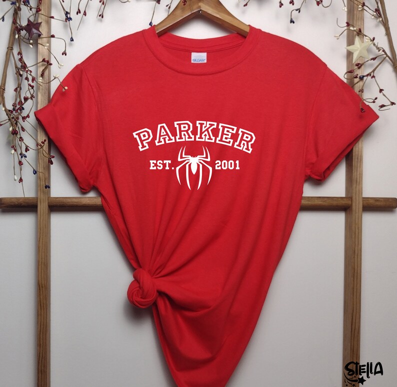 May include: Red t-shirt with white text that reads "Parker Est. 2001" and a white spider graphic.