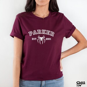 May include: Burgundy t-shirt with white text that reads "Parker Est. 2001" and a white spider graphic.
