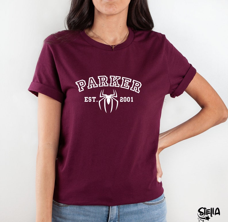 May include: Burgundy t-shirt with white text that reads "Parker Est. 2001" and a white spider graphic.