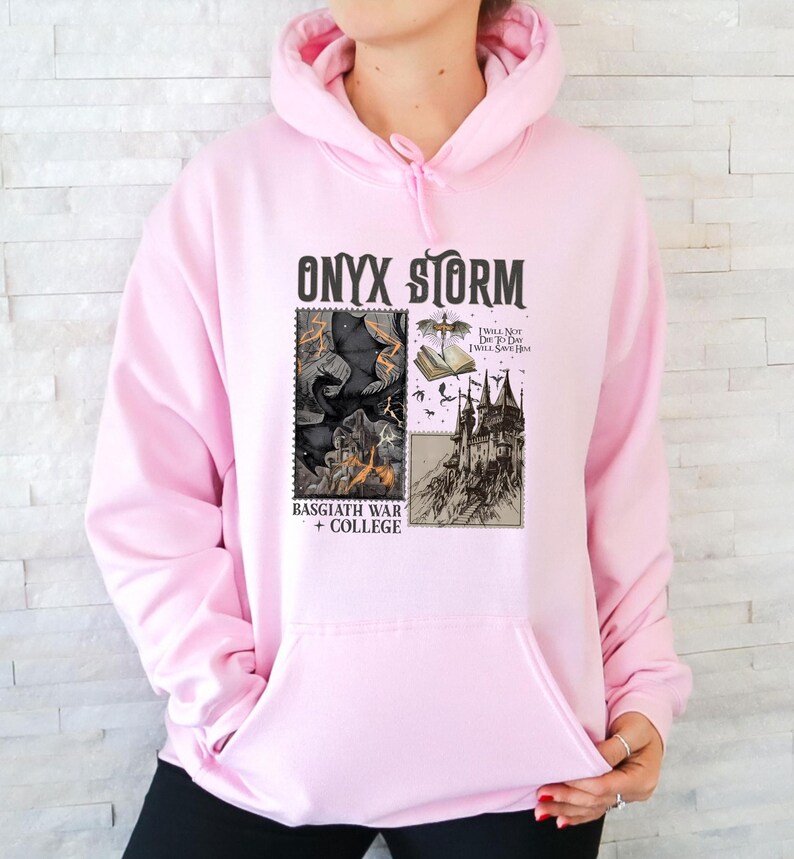 Peut inclure: Sweat-shirt rose avec un imprim&eacute; graphique d'un dragon noir, d'un ch&acirc;teau et le texte "ONYX STORM", "I WILL NOT DIE TO DAY I WILL SAVE HIM", "BASSGIATH WAR + COLLEGE".