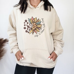 May include: A cream-colored hoodie with a graphic of a sunflower with paw prints and the text "Life Is Better With Dogs".