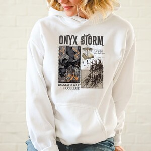 Peut inclure: Sweat-shirt blanc avec un imprim&eacute; graphique noir et blanc d'un ch&acirc;teau et d'un dragon. Le texte "ONYX STORM" est imprim&eacute; en noir en haut du graphique. Le texte "BASSGIATH WAR + COLLEGE" est imprim&eacute; en noir en bas du graphique. Le texte "I WILL NOT DIE TO DAY I WILL SAVE HIM" est imprim&eacute; en noir sur fond blanc dans le coin sup&eacute;rieur droit du graphique.