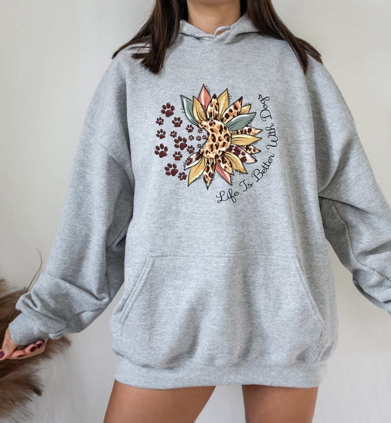 May include: Gray hooded sweatshirt with a sunflower design featuring a leopard print and paw prints. The text "Life Is Better With Dogs" is printed on the sweatshirt.