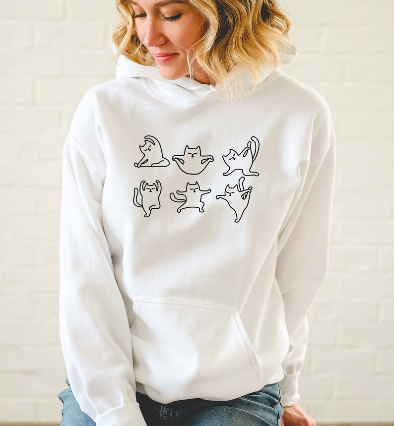 May include: White hooded sweatshirt with a black outline graphic of cats doing yoga poses.