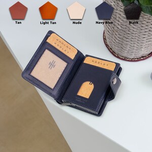 Könnte beinhalten: Eine dunkelblaue Ledergeldbörse mit dem Wort "HOODLY" geprägt auf der Vorderseite. Die Geldbörse ist geöffnet und zeigt einen Kartensteckplatz und ein kleines Fach für Bargeld.