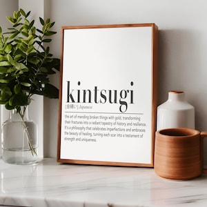 May include: A framed print with a white background and black text. The text reads "kintsugi [金繕い] Japanese the art of mending broken things with gold, transforming their fractures into a radiant tapestry of history and resilience. It's a philosophy that celebrates imperfections and embraces the beauty of healing, turning each scar into a testament of strength and uniqueness."