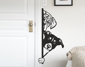 May include: Black and white silhouette wall decal of two dogs peeking around a door frame. The dogs are facing the viewer and have a playful expression.