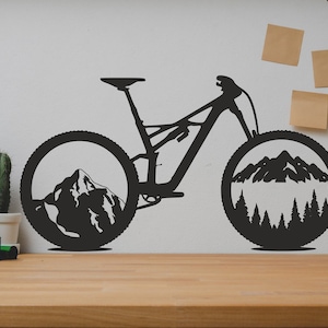 以下が含まれることがあります： 車輪の中に山岳風景が描かれた、黒いシルエットの自転車。自転車は白い壁にかけられており、その下に木の棚がある。