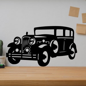 Puede incluir: Silueta negra de un coche antiguo en una pared blanca. El coche tiene una carrocería redondeada y una parrilla grande. El coche es un elemento de decoración del hogar popular.