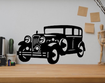 May include: Black silhouette of a vintage car on a white wall. The car has a rounded body style and a large grill. The car is a popular design element for home decor.