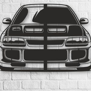 Pode incluir: Silhueta de carro de metal preto montada numa parede de tijolo branco. O carro apresenta uma vista frontal detalhada com faróis, uma grelha e espelhos laterais. A obra de arte é uma peça decorativa.