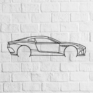 May include: Black metal outline of a sports car mounted on a white brick wall. The car's design is sleek, with visible details of the body, windows, and front grill. The wheels are represented by simple circular outlines.