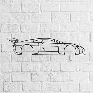 Puede incluir: Arte mural de metal negro que representa el contorno de un coche deportivo con alerón trasero. El diseño del coche es minimalista, con líneas limpias y centrado en la silueta del vehículo. La obra de arte está montada en una pared de ladrillos blancos.