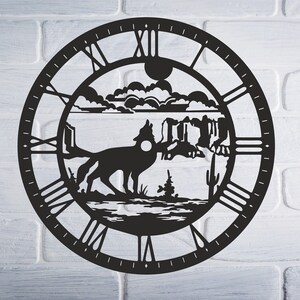 Könnte beinhalten: Schwarze Wanduhr aus Metall mit einer Silhouette eines Kojoten, der in einer Wüstenlandschaft zum Mond heult. Das Zifferblatt der Uhr hat römische Ziffern.
