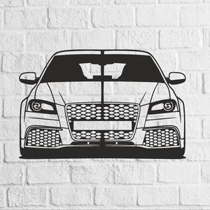 May include: A black and white illustration of a car's front view, mounted on a white brick wall. The car has a detailed grille, headlights, and a sleek, modern design. The artwork is a minimalist representation of a vehicle.