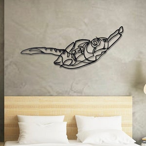 May include: Black metal wall art sculpture of a stylised turtle, hanging on a wall above a bed with white bedding and a wooden headboard. The wall is a light grey colour.