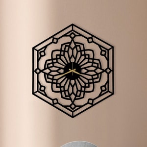 May include: A black geometric wall clock with gold hands, a light gray speaker with a gold stand, a brown ottoman, and a black side table with a round top and a black sphere base.