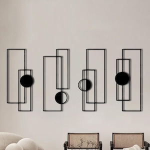 Puede incluir: Un conjunto de cuatro esculturas de pared de metal negro con formas geométricas y círculos. Las esculturas están dispuestas en una fila en una pared blanca.