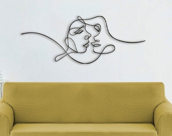 Può includere: Un divano giallo con un decoro murale in linea nera di due volti. Il decoro è un disegno a linea singola di due volti che si guardano.