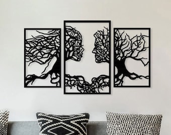 Puede incluir: Un conjunto de tres piezas de arte de pared con siluetas negras de árboles entrelazados con rostros humanos formados dentro de las ramas. La obra de arte se muestra en una pared blanca sobre un sofá gris con almohadas de tiro con patrones en blanco y negro.