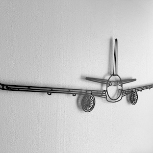 May include: A black metal airplane wall art piece. The artwork features a detailed outline of an airplane, including the fuselage, wings, tail, and wheels. The piece is mounted on a textured white wall, creating a striking contrast.