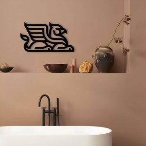 Pode incluir: Arte de parede de metal preto que representa um grifo estilizado, uma criatura m&iacute;tica com a cabe&ccedil;a e as asas de uma &aacute;guia e o corpo de um le&atilde;o. A arte est&aacute; montada em uma parede marrom claro acima de uma banheira branca e uma torneira preta.