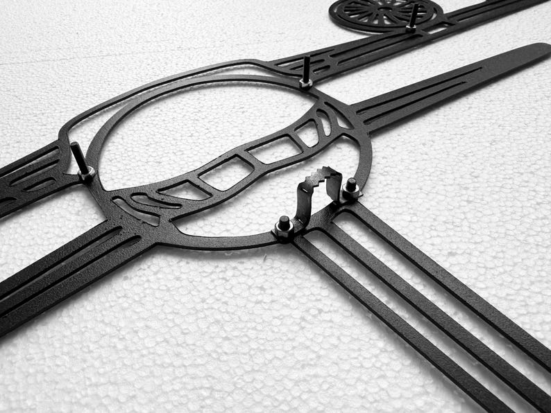 May include: Black metal wall art featuring a stylized lacrosse stick and ball design. The piece has a circular element and several straight, parallel lines, with visible mounting hardware.