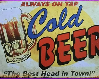 May include: A vintage-style metal sign with a yellow background and a cartoon image of a glass of beer. The sign reads "Always on Tap Cold Beer" in blue and red lettering. The text "The Best Head in Town!" is printed in black at the bottom.
