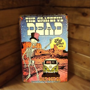 May include: Vintage metal sign featuring a skeleton in a top hat, with the text "The Grateful Dead Fall Tour 1972." The artwork includes a desert landscape, a yellow VW bus, and the date "Sat. Oct. 21."