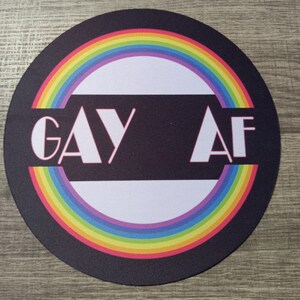 May include: A black round mousepad with a rainbow circle and the text "GAY AF" in white letters with a pink outline.