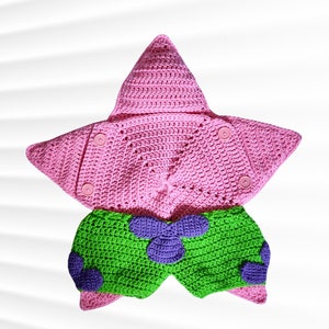 May include: A pink crocheted hooded star-shaped garment with green crocheted pants featuring purple flower accents.