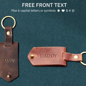 May include: Two brown leather keychains with gold rings. The keychain on the left says "DAD" and the keychain on the right says "DADDY".