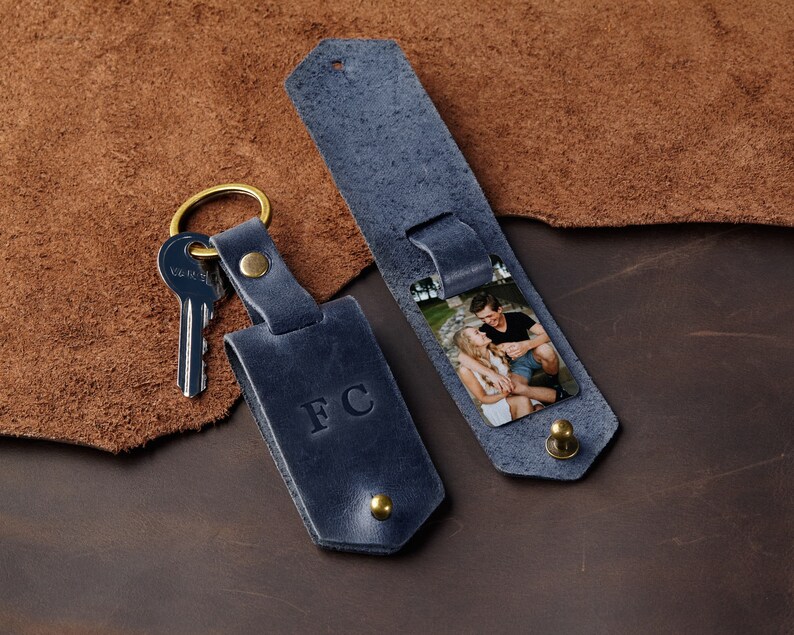 May include: A blue leather keyring with a photo insert and the initials "FC" embossed on the front. The keyring has a brass key ring and a brass snap closure.