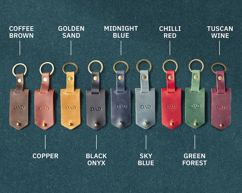 May include: Ten leather keyrings with different coloured leather and metal rings. Each keyring has the word "DAD" embossed on the leather. The colours are coffee brown, golden sand, midnight blue, chilli red, tuscan wine, copper, black onyx, sky blue, green forest.
