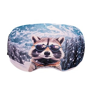 May include: A pair of ski goggles featuring a raccoon wearing sunglasses against a snowy mountain backdrop. The goggles have a blue and white design with a black strap. The raccoon is the focal point, adding a playful touch to the winter sports accessory.