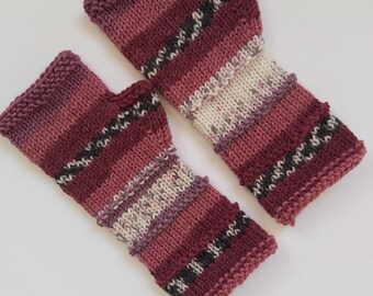 May include: A pair of knitted fingerless gloves in a pink, white, and black striped pattern.