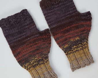 May include: A pair of fingerless gloves featuring a gradient color pattern that transitions from dark purple at the top to deep red, mustard yellow, and light beige at the ribbed cuffs. The knit texture is consistent throughout both gloves.