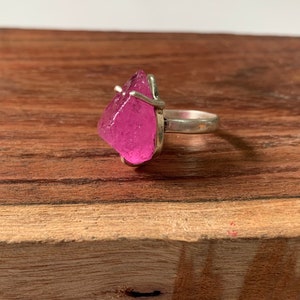 Peut inclure: Une bague en argent avec un cristal rose. Le cristal est de forme irrégulière et est serti dans une monture simple en fil.