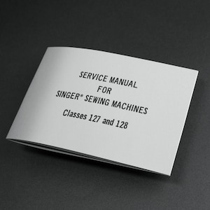 May include: A white service manual for Singer sewing machines. The cover reads "SERVICE MANUAL FOR SINGER* SEWING MACHINES Classes 127 and 128" in black text. The manual is open, revealing the inside pages.