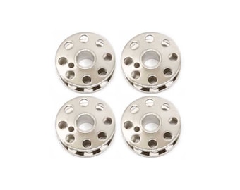 May include: Four circular silver-colored metal sewing machine bobbins arranged in a two-by-two grid. Each bobbin features a central hole surrounded by a series of smaller circular perforations along the top edge and a smooth metallic finish.