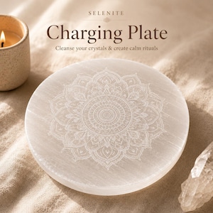 Könnte beinhalten: Eine runde, weiße Selenit-Ladeplatte mit einem detaillierten Mandala-Design, das in die Oberfläche geätzt ist. Auf der Platte steht "Charging Plate" mit dem Text "Cleanse your crystals & create calm rituals". Links ist eine brennende Kerze zu sehen.