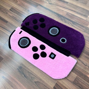 May include: Two plush Nintendo Switch controller rugs. One is purple and the other is pink.