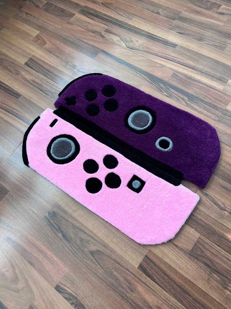 May include: Two plush Nintendo Switch controller rugs. One is purple and the other is pink.